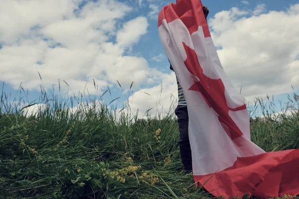 Szczęśliwy chłopiec machając flagą Kanady podczas biegania — Zdjęcie stockowe