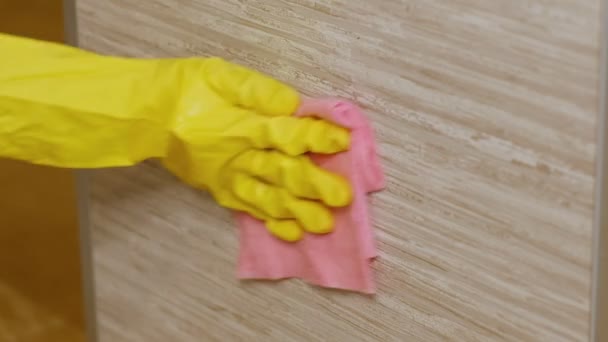 Detailní záběr na ženské ruce ve žlutých ochranných gumových rukavicích čištění kuchyňských skříněk s houbou.