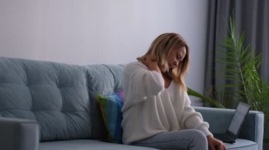 Yorgun Asyalı kadın koltukta oturur, boynu ağrıyan, omuzlarına dokunan, kendine masaj yapan ve acı çeken bir yüzle esneme hareketleri yapan yorgun bir şekilde. Ofis Sendromu.