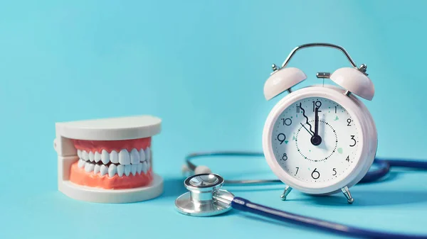 Modelo de dentes brancos com despertador no fundo azul. para a saúde dentária. Conceito de dia de dentista. espaço de cópia para texto. — Fotografia de Stock