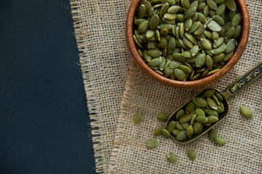 Tahta bir kasede kabak çekirdeği ve antika bir kepçe. Siyah bir arkaplana yaklaş. metin için boşluk kopyala