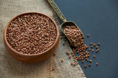 Karabuğday ahşap bir kasede ve kaliteli bir kepçeyle yetişir. Siyah bir arkaplana yaklaş. metin için boşluk kopyala