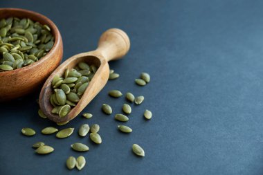 Tahta bir kasede kabak çekirdeği ve antika bir kepçe. Siyah bir arkaplana yaklaş. metin için boşluk kopyala