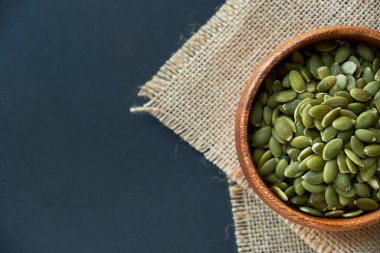 Tahta bir kasede kabak çekirdeği ve antika bir kepçe. Siyah bir arkaplana yaklaş. metin için boşluk kopyala
