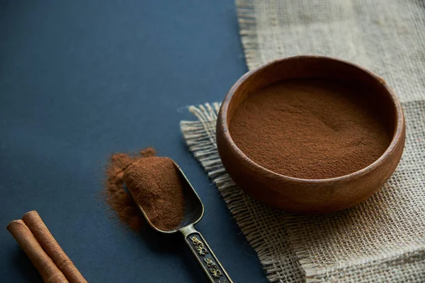 Tarçın çubukları, kenevir ipiyle sade bir şekilde bağlanmış. Ahşap bir kase ve eski bir kepçe içinde yer tarçın. Siyah bir arkaplana yaklaş. metin için boşluk kopyala. Yan görünüm, düz uzanma.