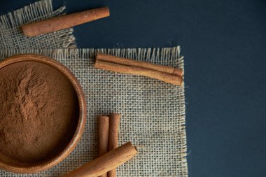 Tarçın çubukları, kenevir ipiyle sade bir şekilde bağlanmış. Ahşap bir kase ve eski bir kepçe içinde yer tarçın. Siyah bir arkaplana yaklaş. metin için boşluk kopyala. Üst manzara, düz uzanma.