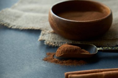 Tarçın çubukları, kenevir ipiyle sade bir şekilde bağlanmış. Ahşap bir kase ve eski bir kepçe içinde yer tarçın. Siyah bir arkaplana yaklaş. metin için boşluk kopyala. Yan görünüm, düz uzanma.