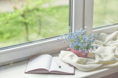 Beyaz, sıcak ekose battaniye ve not defteri, ahşap kırsal bankta gözlük. Fotoğraf tonlu, seçici odaklanma. Samimi ev hayatı: Bahar çiçekleri, pencere kenarında sıcak ekoseli.