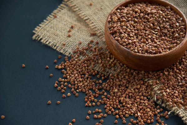 Karabuğday ahşap bir kasede ve kaliteli bir kepçeyle yetişir. Siyah bir arkaplana yaklaş. metin için boşluk kopyala