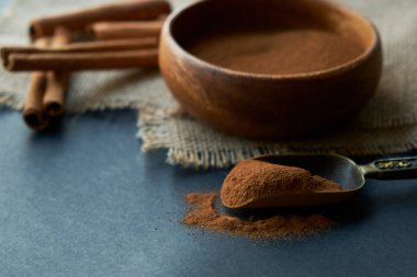 Tarçın çubukları, kenevir ipiyle sade bir şekilde bağlanmış. Ahşap bir kase ve eski bir kepçe içinde yer tarçın. Siyah bir arkaplana yaklaş. metin için boşluk kopyala. Yan görünüm, düz uzanma.