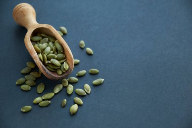 Tahta bir kasede kabak çekirdeği ve antika bir kepçe. Siyah bir arkaplana yaklaş. metin için boşluk kopyala