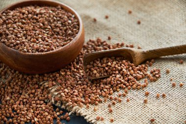 Karabuğday ahşap bir kasede ve kaliteli bir kepçeyle yetişir. Siyah bir arkaplana yaklaş. metin için boşluk kopyala