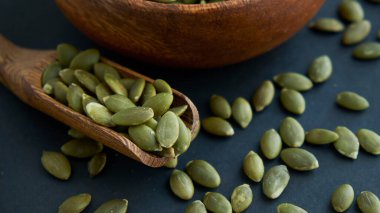 Tahta bir kasede kabak çekirdeği ve antika bir kepçe. Siyah bir arkaplana yaklaş. metin için boşluk kopyala