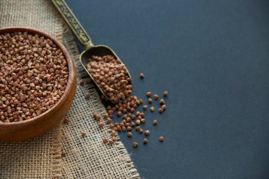 Karabuğday ahşap bir kasede ve kaliteli bir kepçeyle yetişir. Siyah bir arkaplana yaklaş. metin için boşluk kopyala