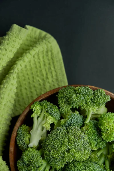 Fresh Broccoli in wooden bowl and seed oil in rustic style. Close up on a black background. copy space for text. Top view, flat lay.