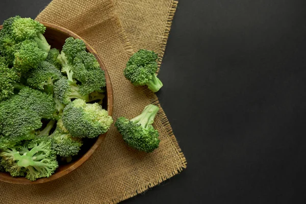 Fresh Broccoli in wooden bowl and seed oil in rustic style. Close up on a black background. copy space for text. Top view, flat lay. — Stock Photo, Image