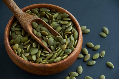 Tahta bir kasede kabak çekirdeği ve antika bir kepçe. Siyah bir arkaplana yaklaş. metin için boşluk kopyala