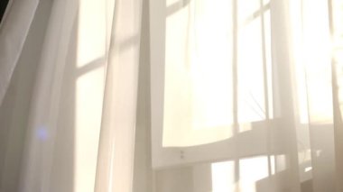 Odadaki açık pencereden rüzgar esiyor. Pencerenin yanında beyaz tül sallıyordu. Güneş ışınları şeffaf tüllerin içinden parlıyor.