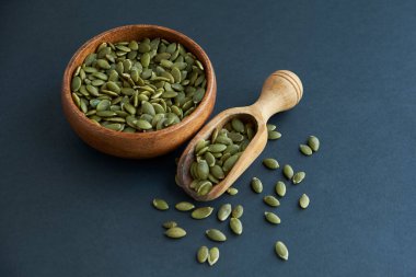 Tahta bir kasede kabak çekirdeği ve antika bir kepçe. Siyah bir arkaplana yaklaş. metin için boşluk kopyala