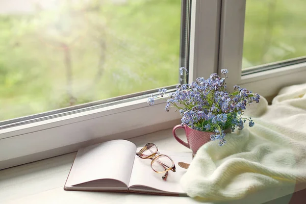 white warm plaid blanket and notebook, glasses on wooden rustic bench. Photo toned, selective focus. Cozy home still life: spring flowers with warm plaid on windowsill