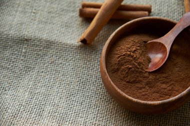 Tarçın çubukları, kenevir ipiyle sade bir şekilde bağlanmış. Ahşap bir kase ve eski bir kepçe içinde yer tarçın. Siyah bir arkaplana yaklaş. metin için boşluk kopyala. Üst manzara, düz uzanma.