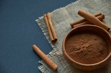 Tarçın çubukları, kenevir ipiyle sade bir şekilde bağlanmış. Ahşap bir kase ve eski bir kepçe içinde yer tarçın. Siyah bir arkaplana yaklaş. metin için boşluk kopyala. Üst manzara, düz uzanma.