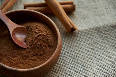 Tarçın çubukları, kenevir ipiyle sade bir şekilde bağlanmış. Ahşap bir kase ve eski bir kepçe içinde yer tarçın. Siyah bir arkaplana yaklaş. metin için boşluk kopyala. Yan görünüm, düz uzanma.