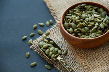 Tahta bir kasede kabak çekirdeği ve antika bir kepçe. Siyah bir arkaplana yaklaş. metin için boşluk kopyala