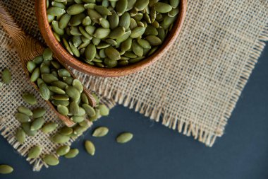 Tahta bir kasede kabak çekirdeği ve antika bir kepçe. Siyah bir arkaplana yaklaş. metin için boşluk kopyala