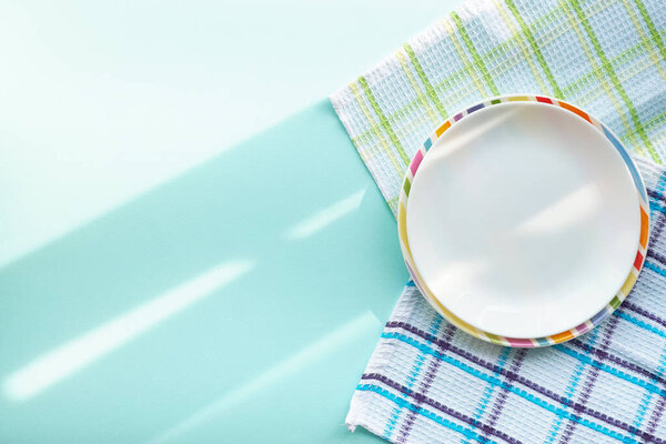 white empty plate on a blue background, covered with the rays of the morning sun