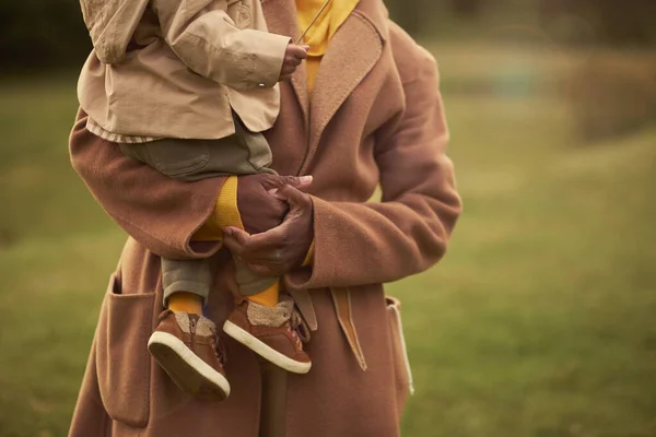 Мама держит ребенка на руках, гуляет в осеннем парке. — стоковое фото