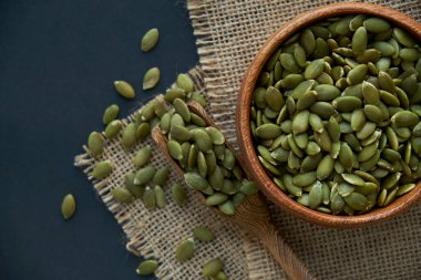 Tahta bir kasede kabak çekirdeği ve antika bir kepçe. Siyah bir arkaplana yaklaş. metin için boşluk kopyala