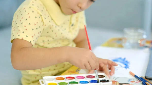 Piccolo ragazzo carino disegna con matite. il bambino è impegnato in creatività a casa — Foto Stock