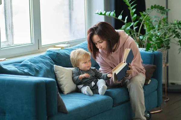 Mor läser en bok barnet i soffan. innan du somnar. ta hand om barn. mödrar älskar sin dotter — Stockfoto