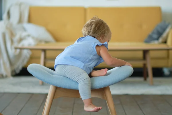 Портрет блондинки блакитноокої дівчини 1 рік сидить на синьому стільці. Мила маленька дитина грає вдома в кімнаті . — стокове фото