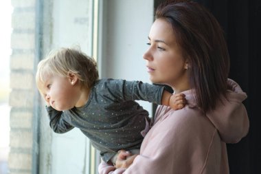 Annesinin kucağında bebeğini pencereden dışarı bakarken çekilmiş yakın plan fotoğrafı.