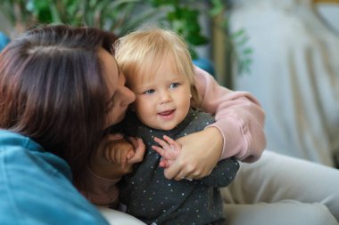 Sevgi dolu bir aile. Anne ve çocuk oynuyorlar, öpüşüyorlar ve sarılıyorlar.