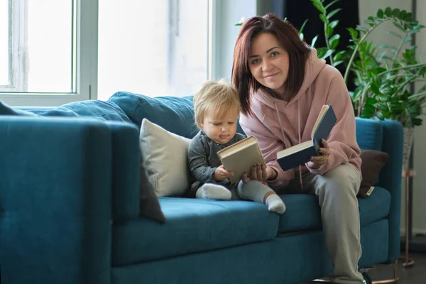 Mor läser en bok barnet i soffan. innan du somnar. ta hand om barn. mödrar älskar sin dotter — Stockfoto