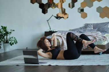 Çevrimiçi Eğitim. Evde egzersiz yapan, dizüstü bilgisayarda video izleyen genç bir kadın..