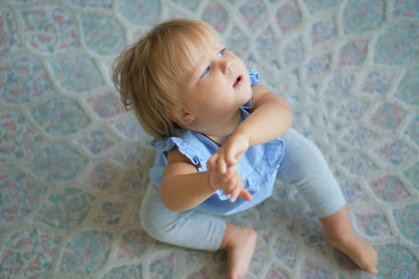 Barndom, barndom och människor koncept. En lycklig liten flicka som sitter på mattan hemma. vy ovanifrån — Stockfoto