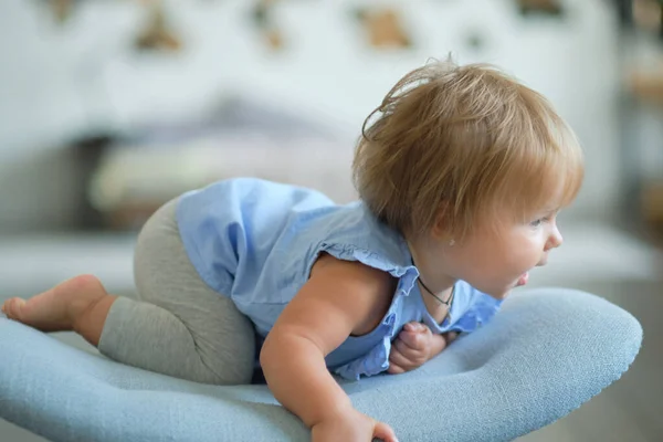 Porträtt av en blond blåögd flicka 1 år gammal sitter på en blå stol. — Stockfoto