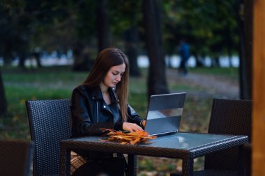 Dizüstü bilgisayarlı gülümseyen ve akıllı telefondan müşteriyle konuşan güzel çekici bir kadın, ofis dışındaki kahve dükkanında, İş Konsepti 'nde, Sıcak Ton' da başarılı bir iş için fikir ve gereksinim sahibi olmak için çalışıyor.