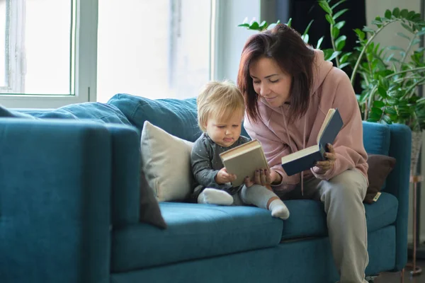 Mother reading a book the baby in sofa. before going to sleep. taking care of children. mothers love for her daughter