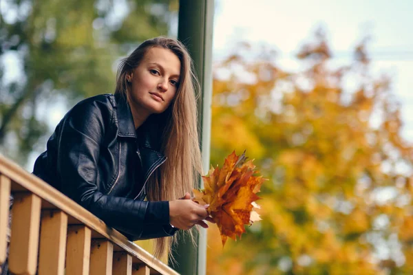 Jonge vrouw met herfst bladeren in de hand en vallen gele esdoorn tuin achtergrond — Stockfoto