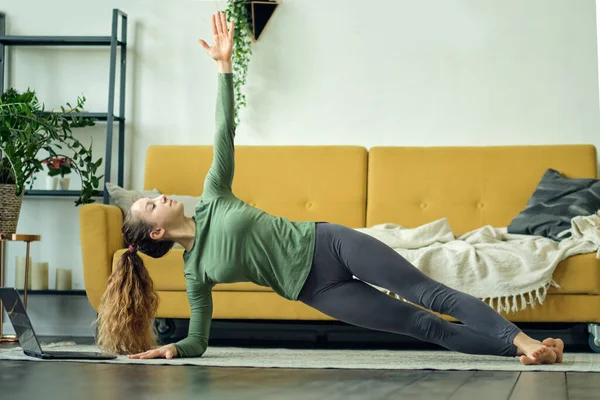 Bella giovane donna che fa yoga a casa. Allenamento fitness online. — Foto Stock