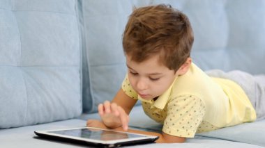 Küçük bir çocuk oyunlar ve çizgi filmler için tablet kullanıyor.