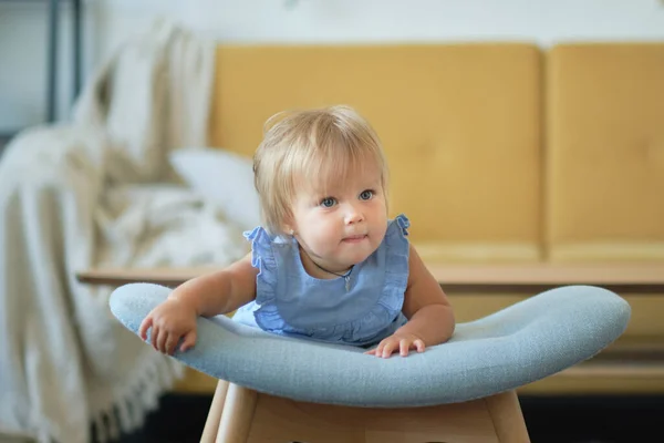 Lilla blåögda flicka lär sig att gå genom att hålla i stolen. Glad baby ansikte — Stockfoto