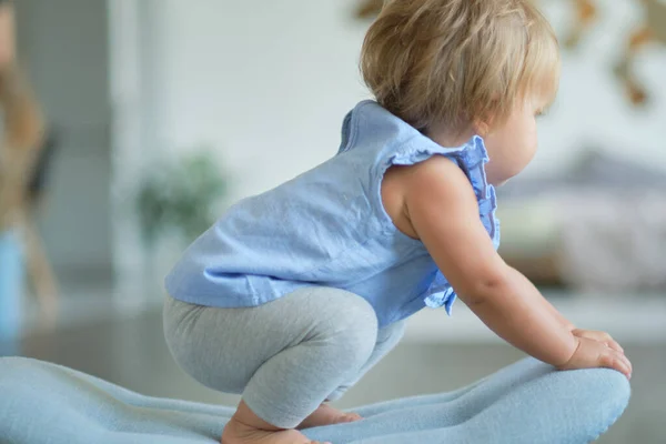 Porträtt av en blond blåögd flicka 1 år gammal sitter på en blå stol. — Stockfoto