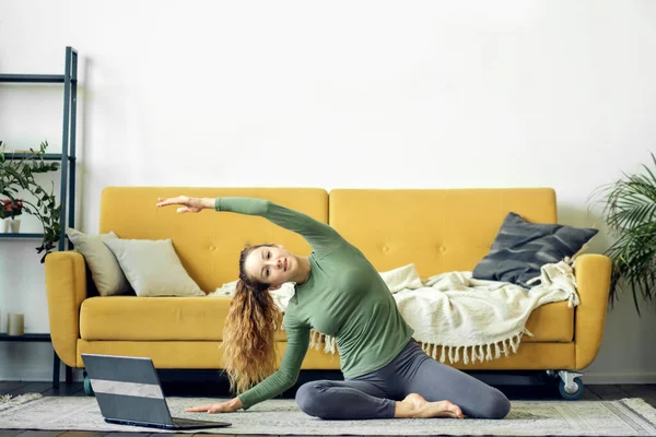 Gyönyörű fiatal nő jógázik otthon. Fitnesz képzés online. — Stock Fotó