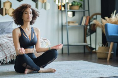 Spor giyimli çekici Afro-Amerikan kız yoga yapıyor ve gülümsüyor..